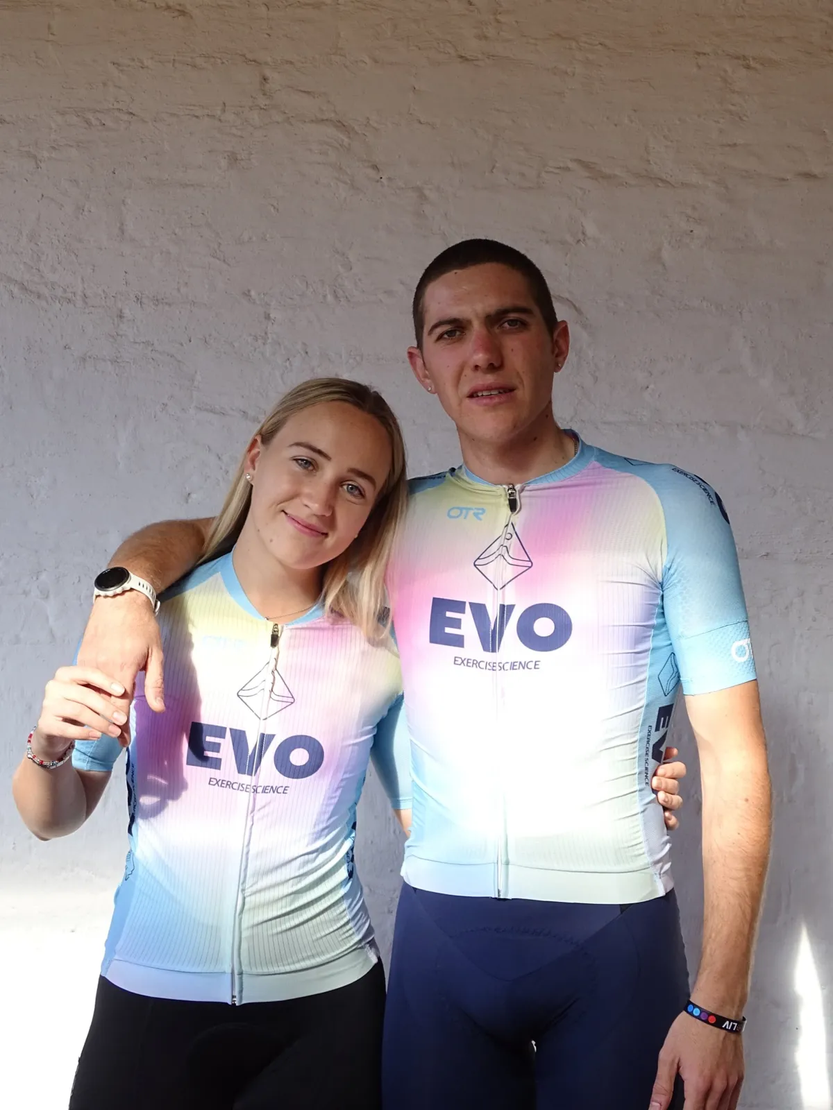 Two athletes in matching EVO kit standing against a white wall