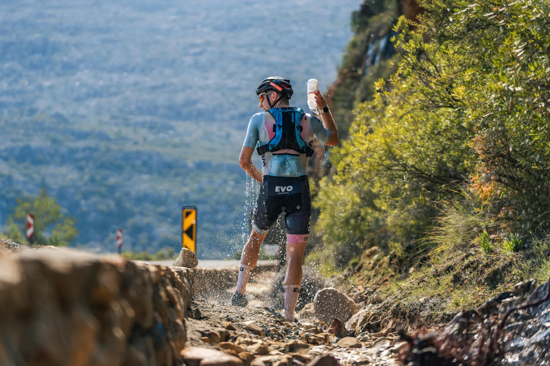 EVO cyclist cooling off with water beside a rocky mountain-pass road
