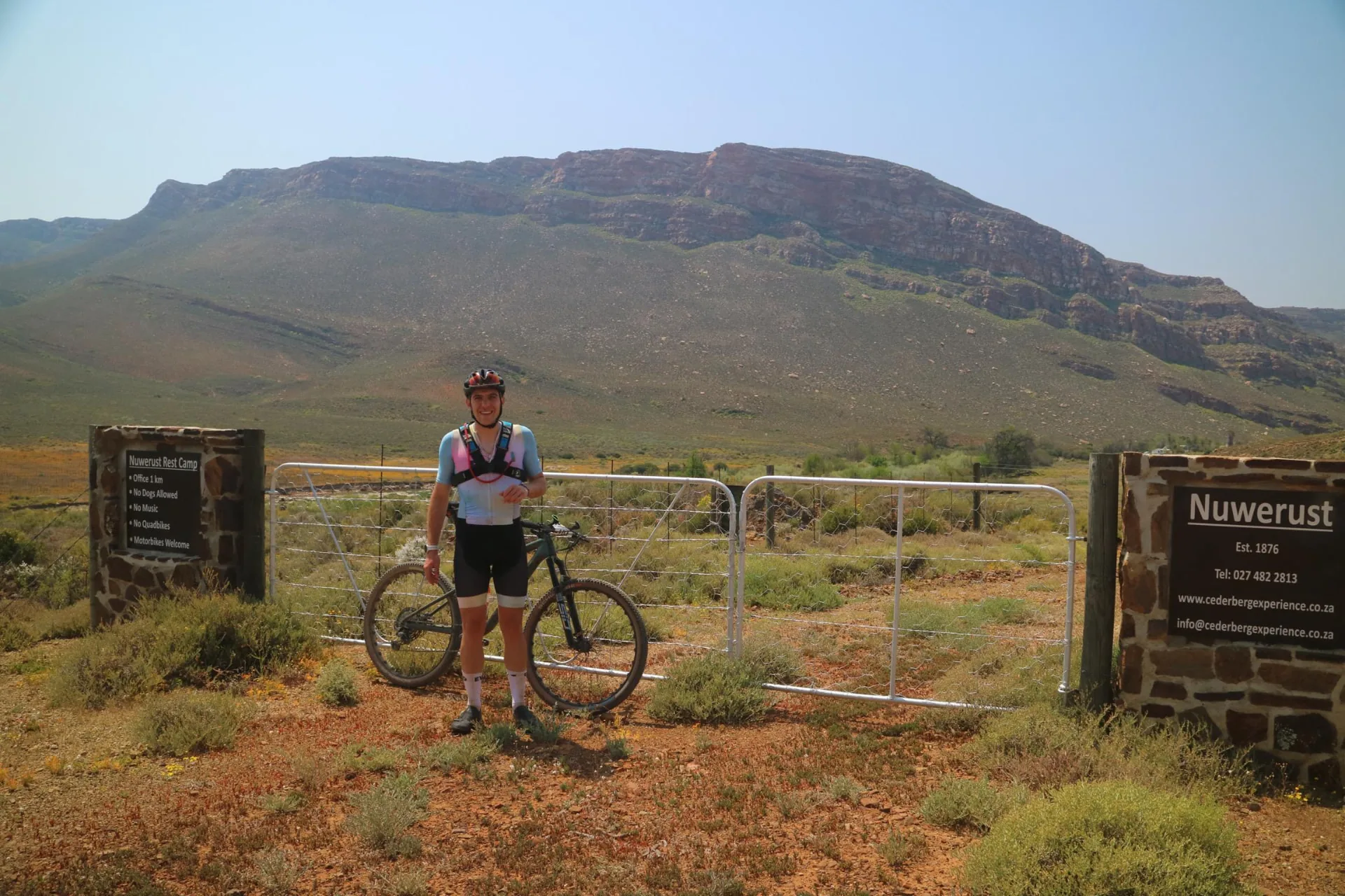 Cyclist with a mountain bike at the Nuwerust gate beneath the Cederberg mountains